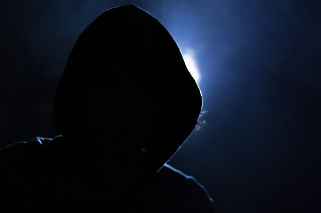Silhouetted hacker with a light behind them